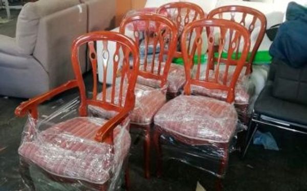 Seis sillas de comedor de madera oscura con asiento tapizado, protegidas con plástico