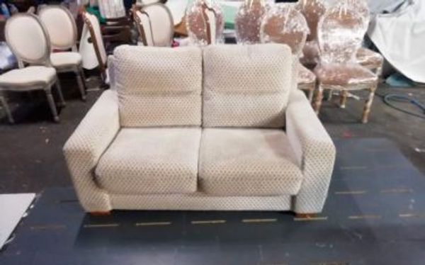 Sofá de dos plazas tapizado en beige con estampado geométrico sutil