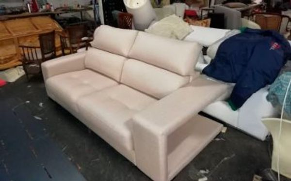 Sofá de tres plazas tapizado en beige claro con cabezales reclinables